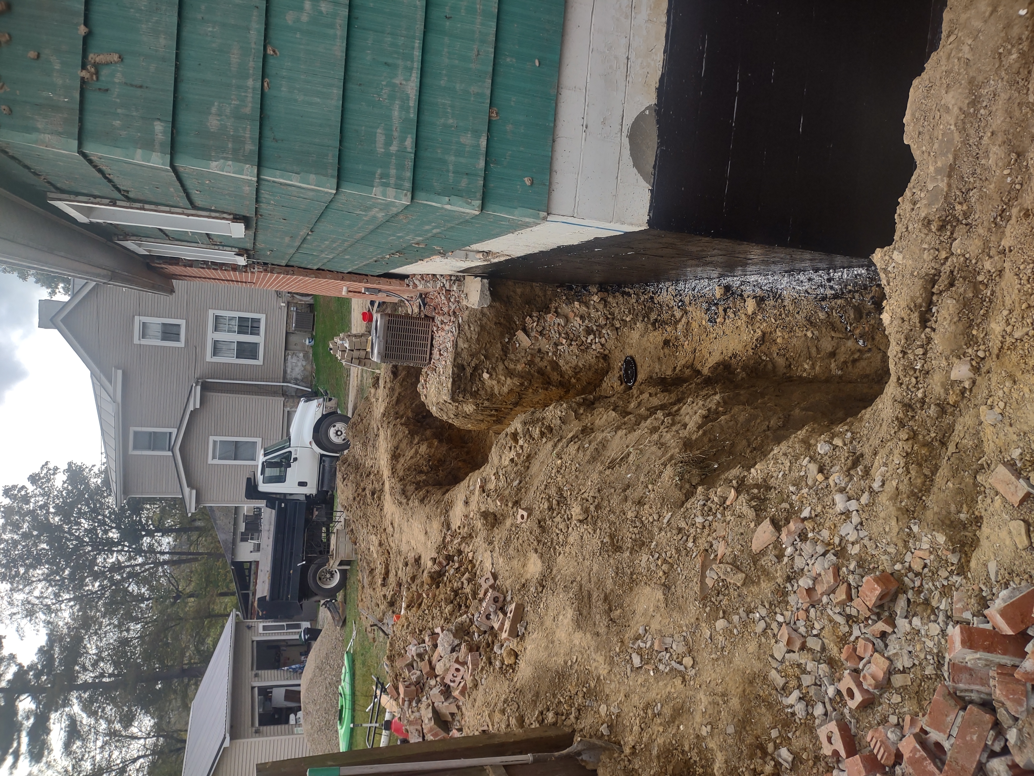 Wider shot showing full excavation depth alongside teal house