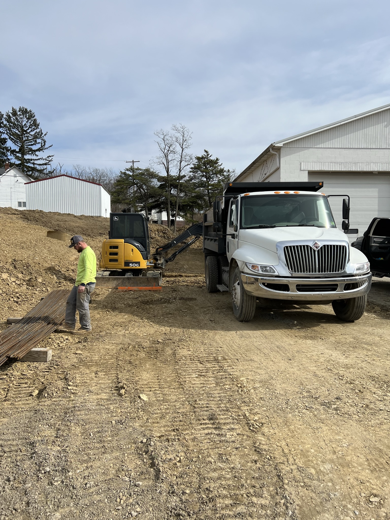 Crew with mini ex and dump truck on site