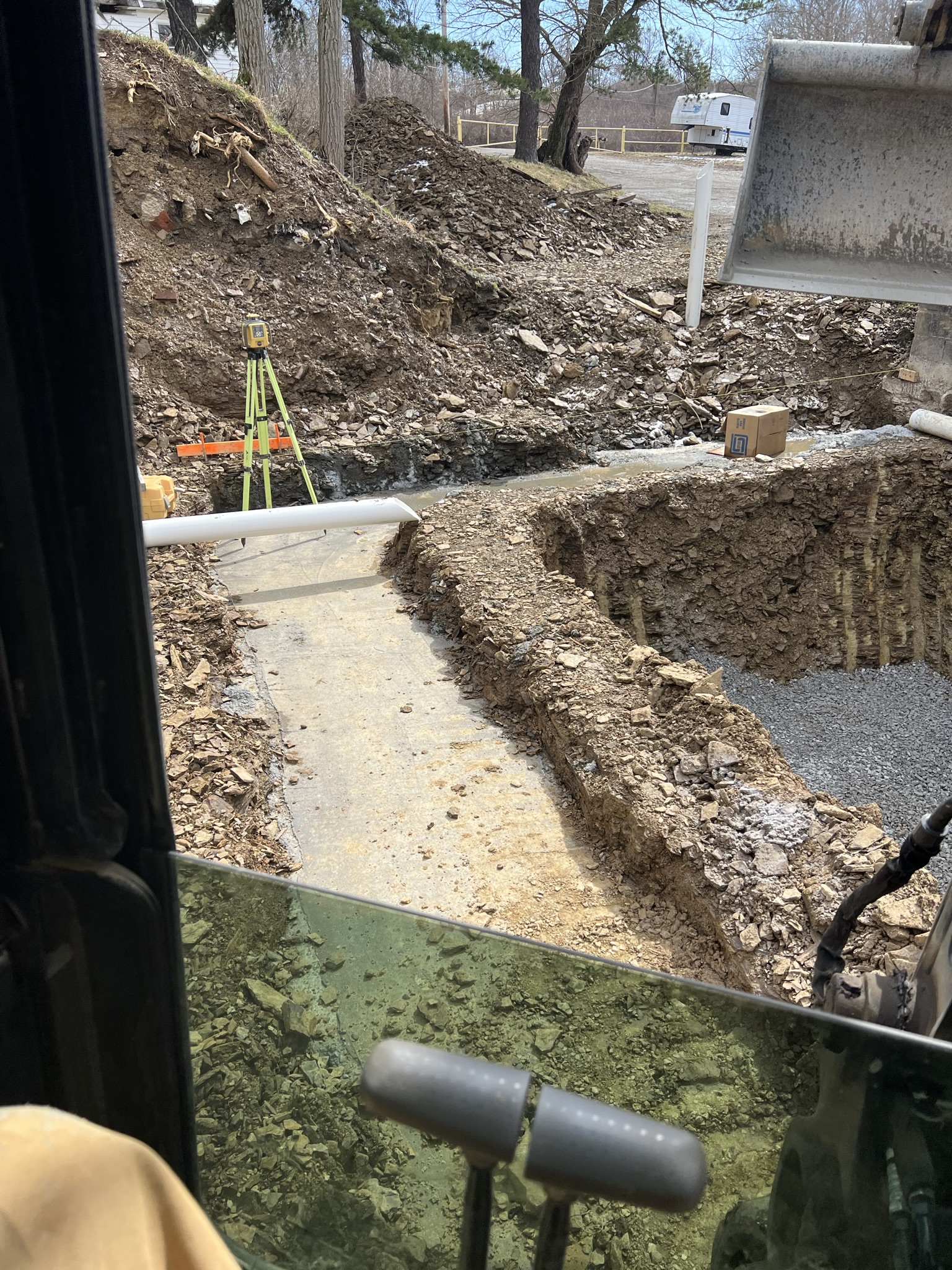 Laser level set up with footings and gravel base visible