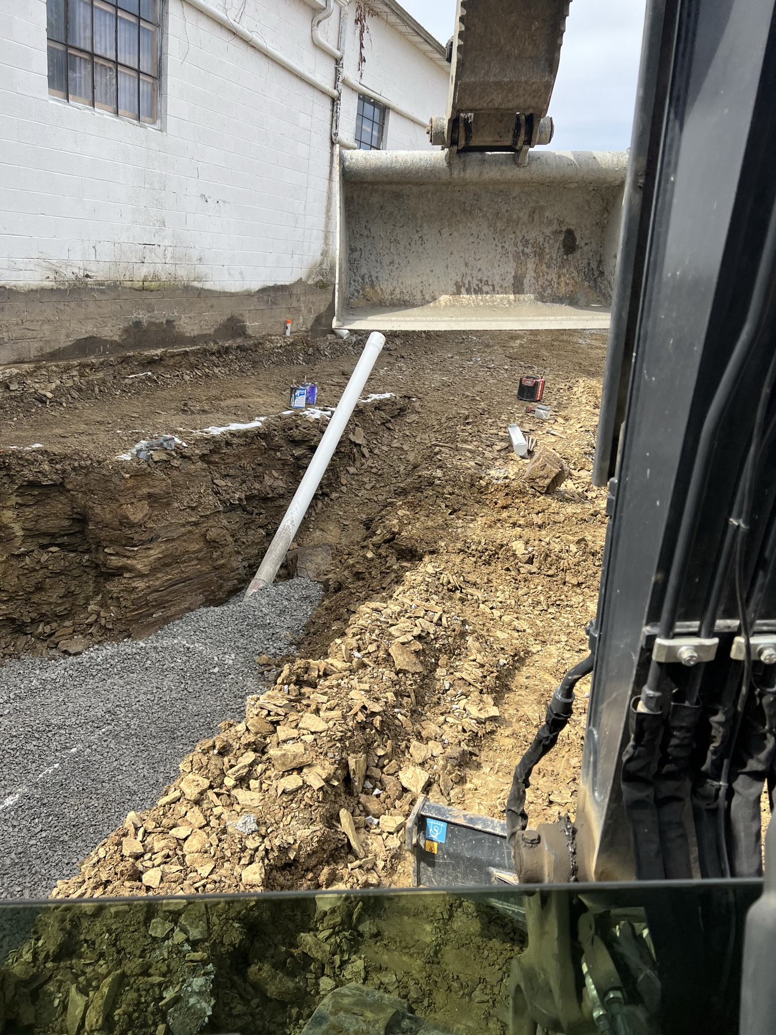 Plumbing rough-in pipe laid across excavation