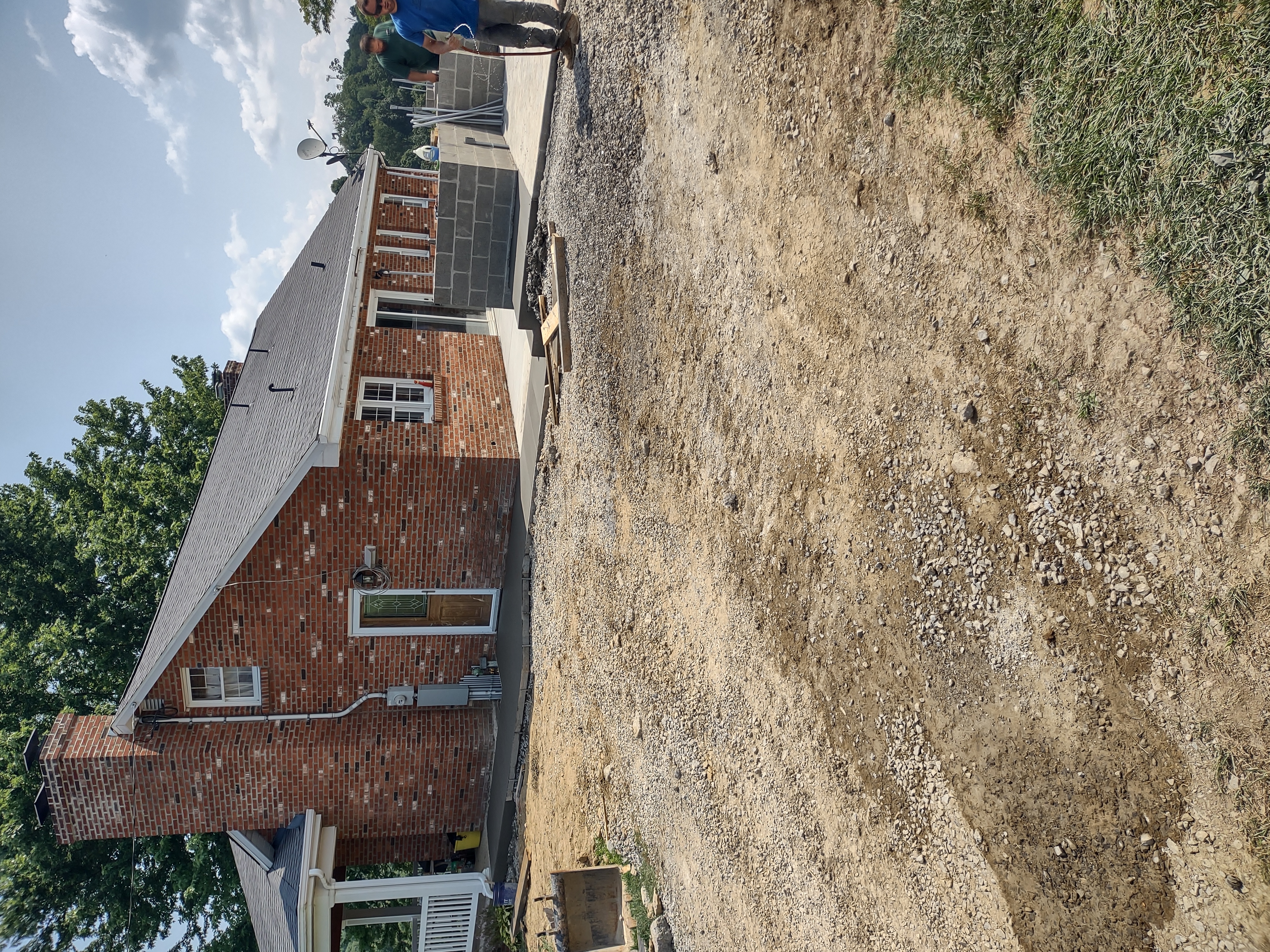 Site prep with block wall framing and crew at brick home