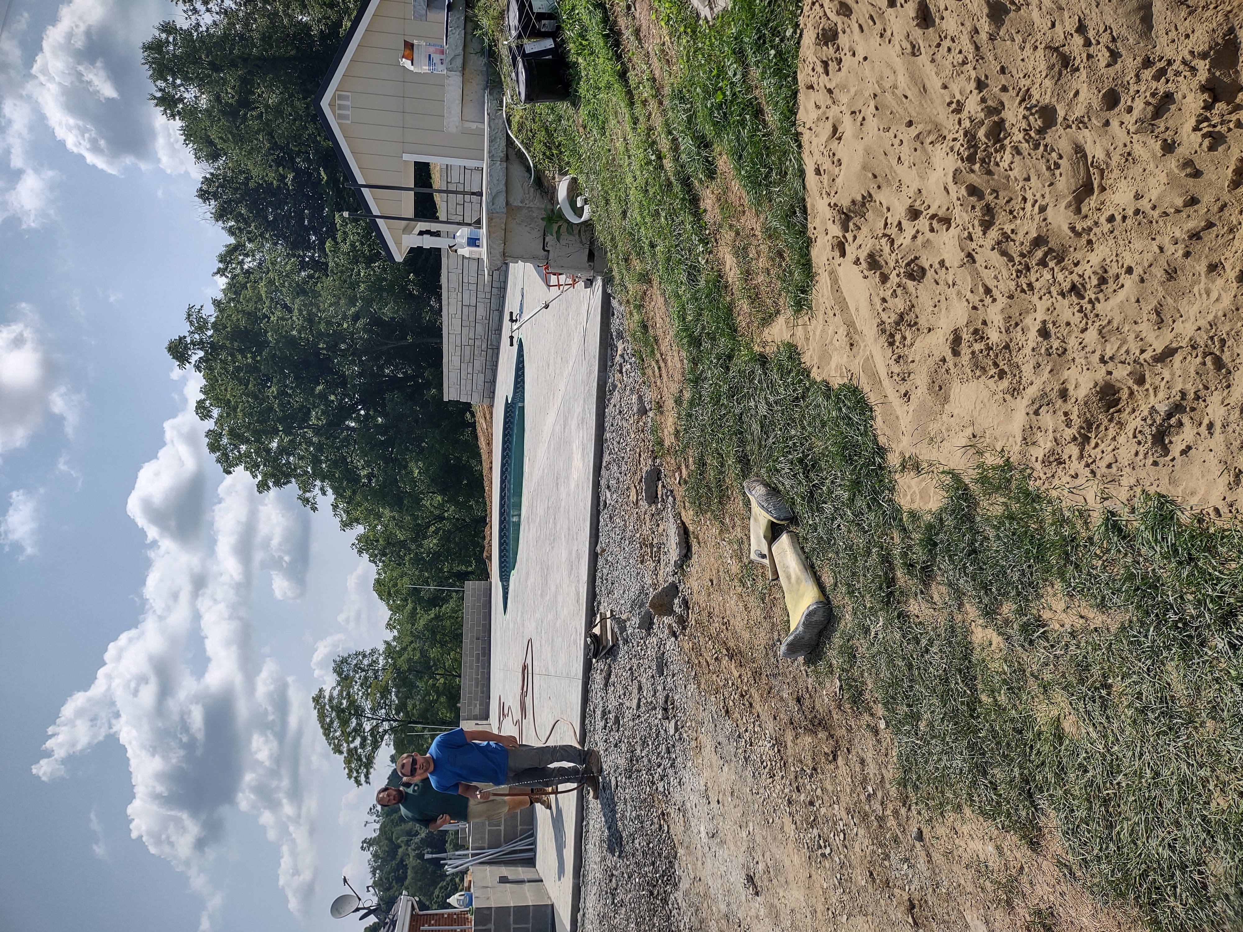 Completed pool patio with crew standing by and retaining wall in background
