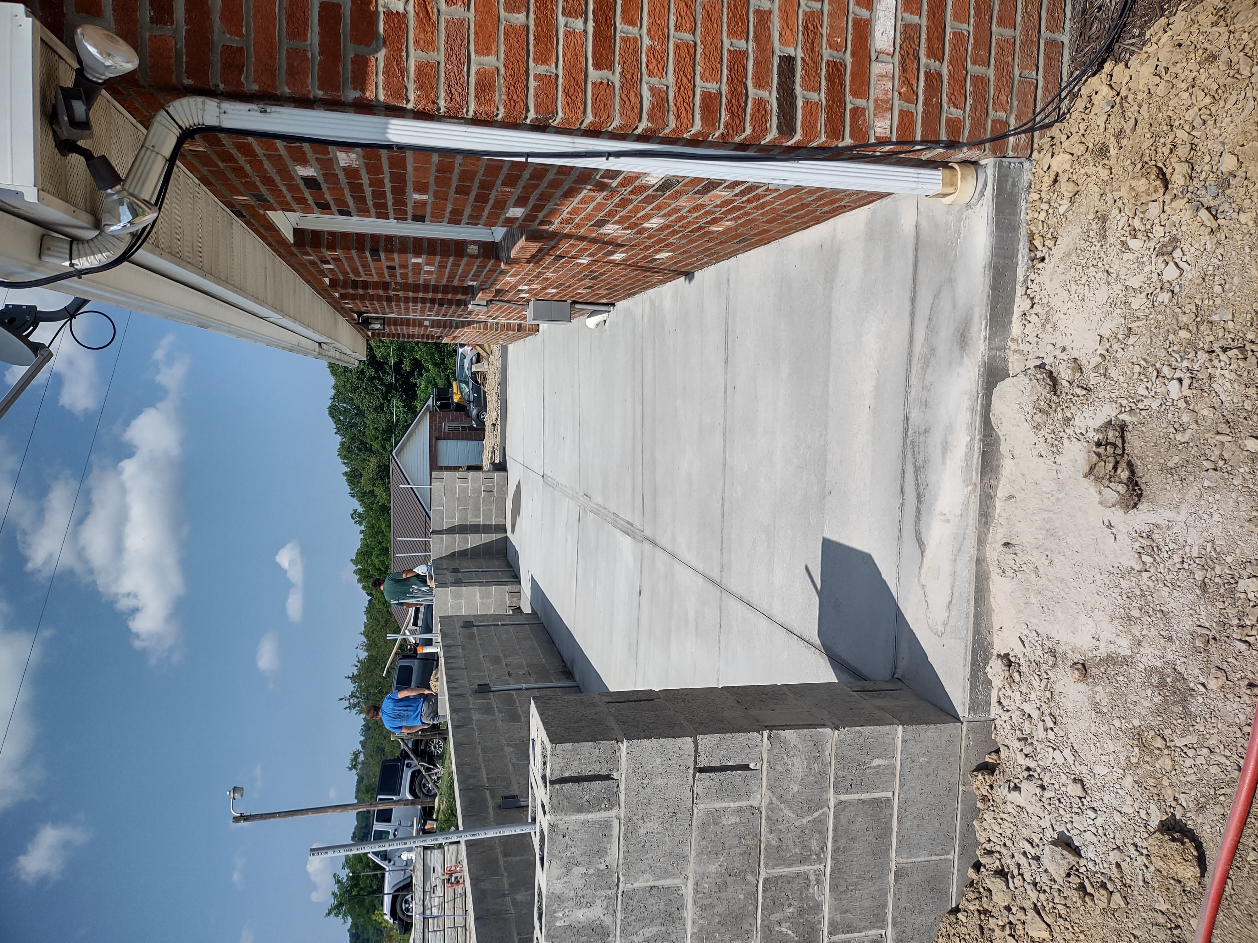 Freshly poured concrete lower porch alongside brick home