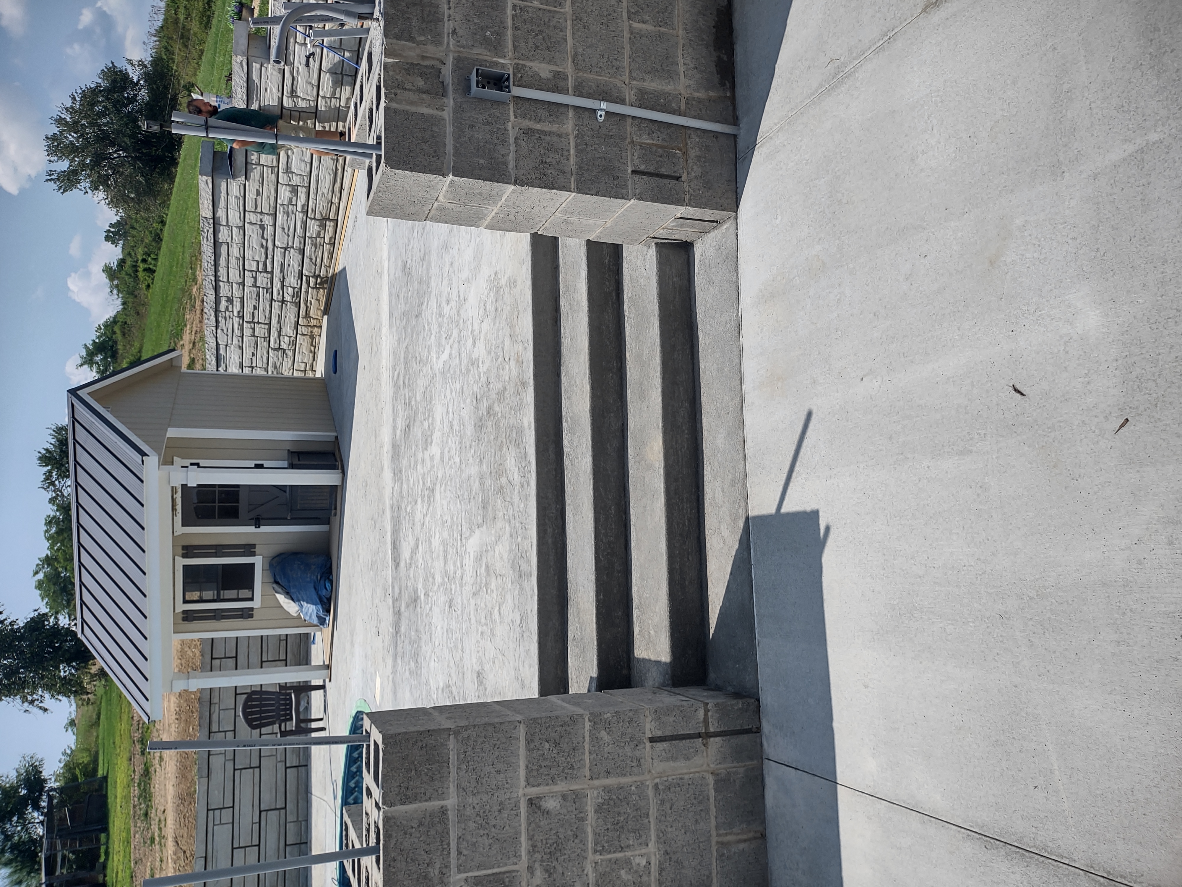 Finished concrete steps leading up to pool patio with pool house in background