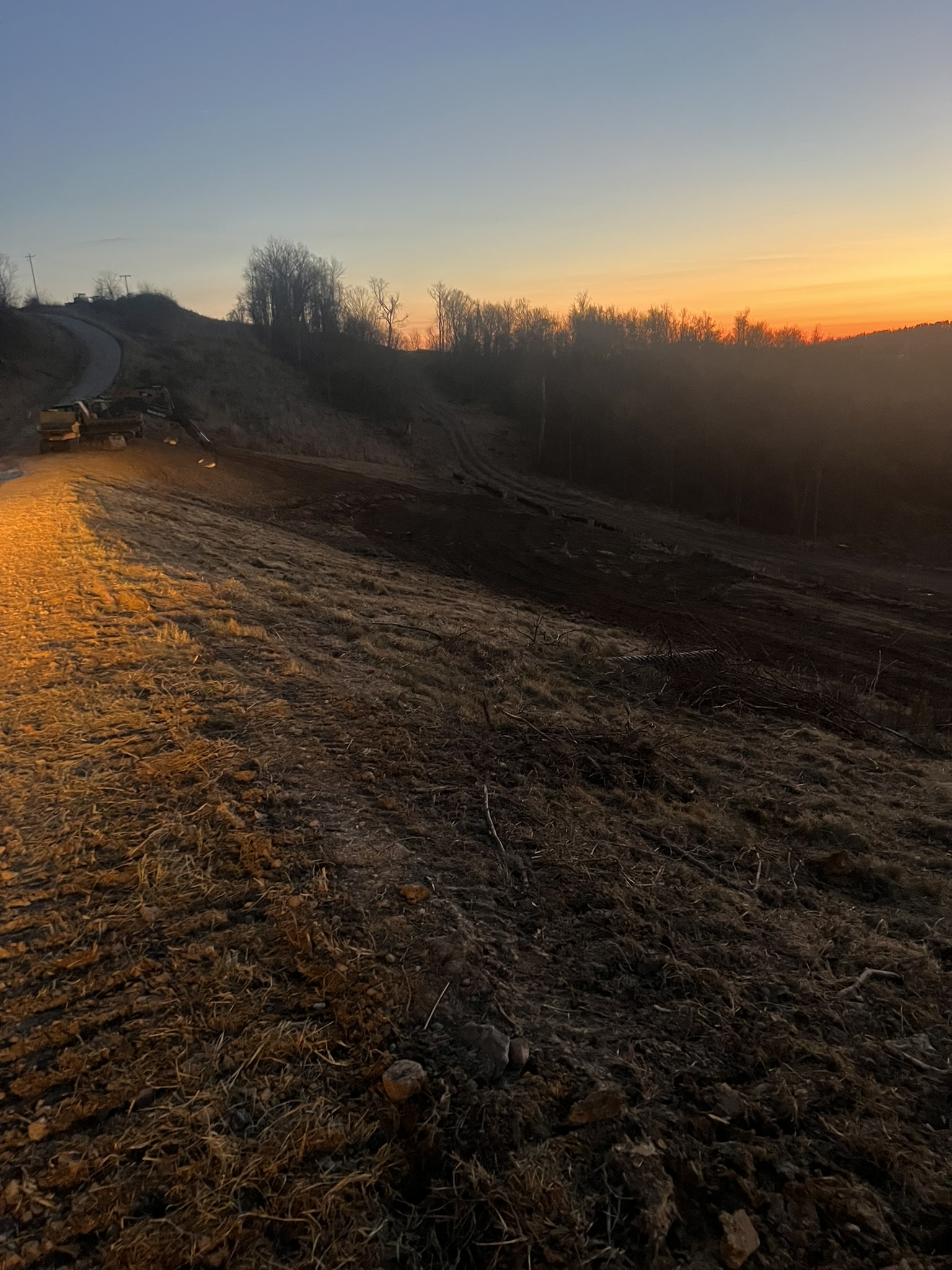 Sunset shot of seeded and mulched slopes with access road and equipment