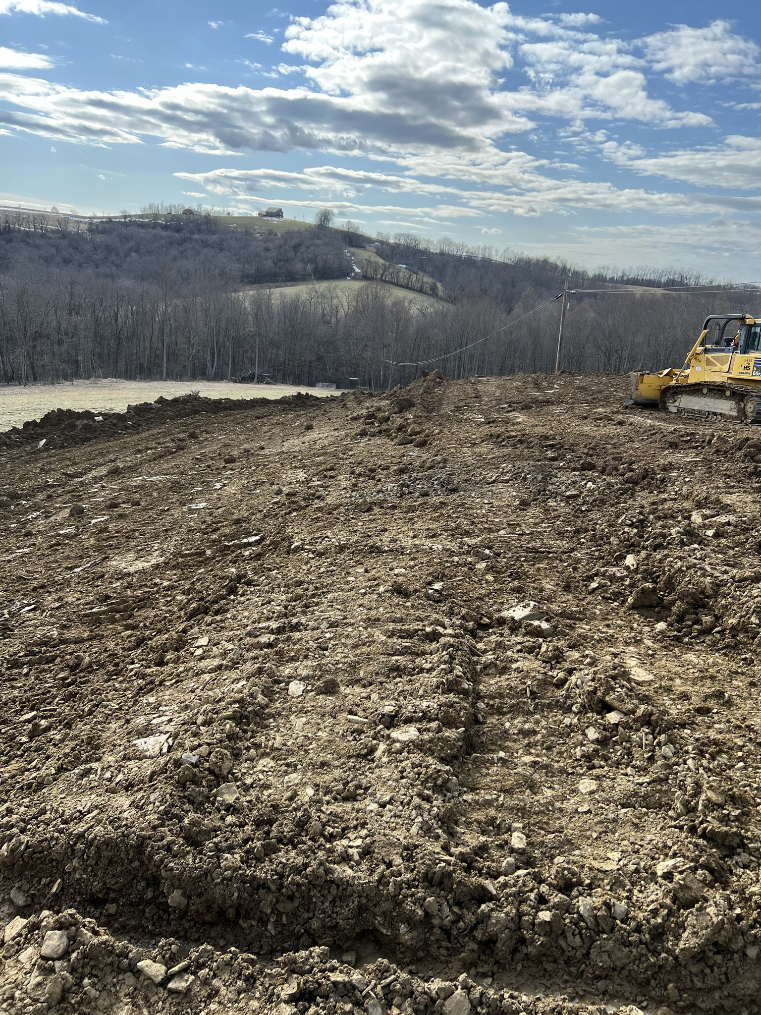 Gravel access road with seeded slopes and pink survey stakes