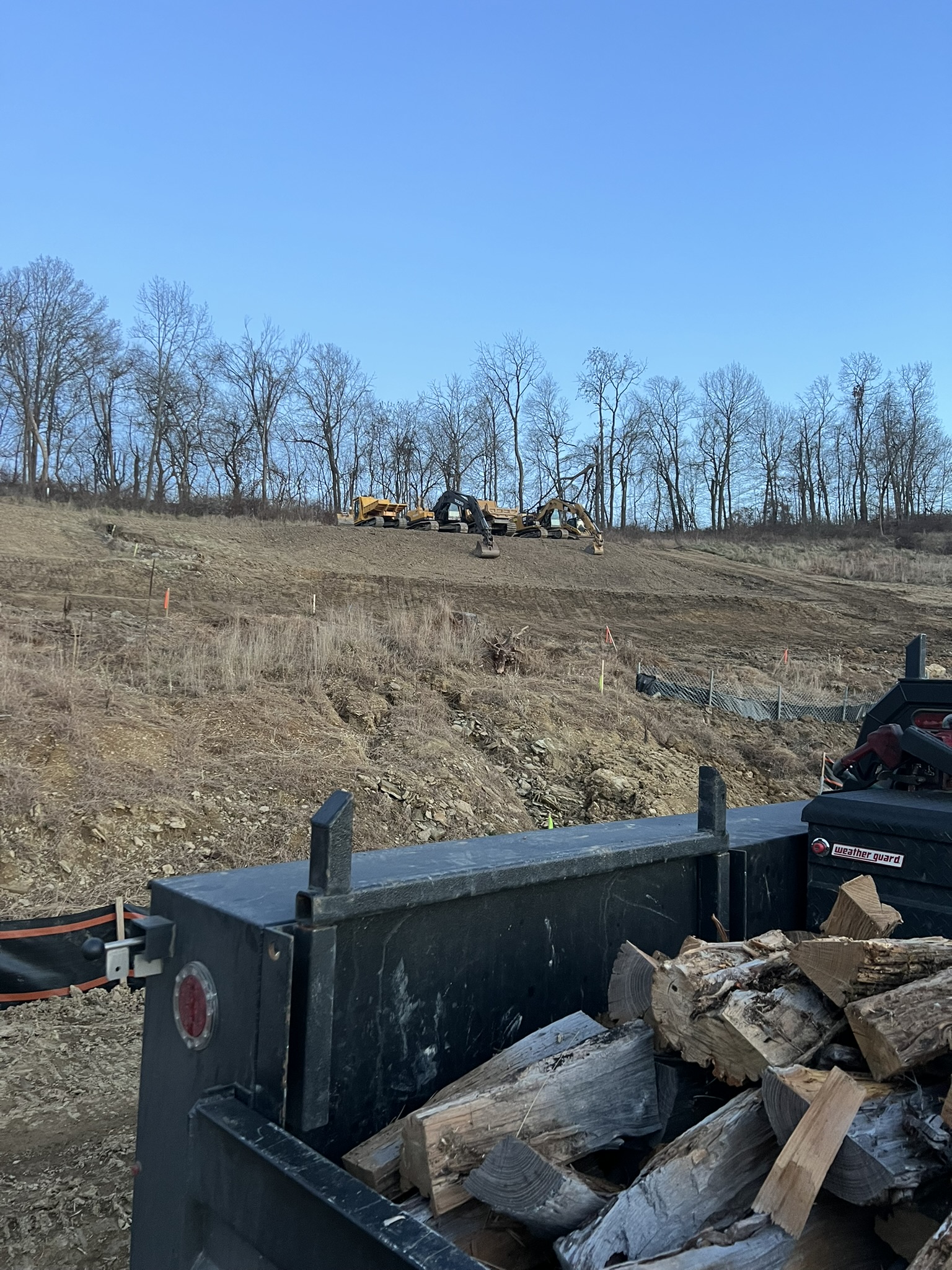 Two CAT excavators working the hillside from road below