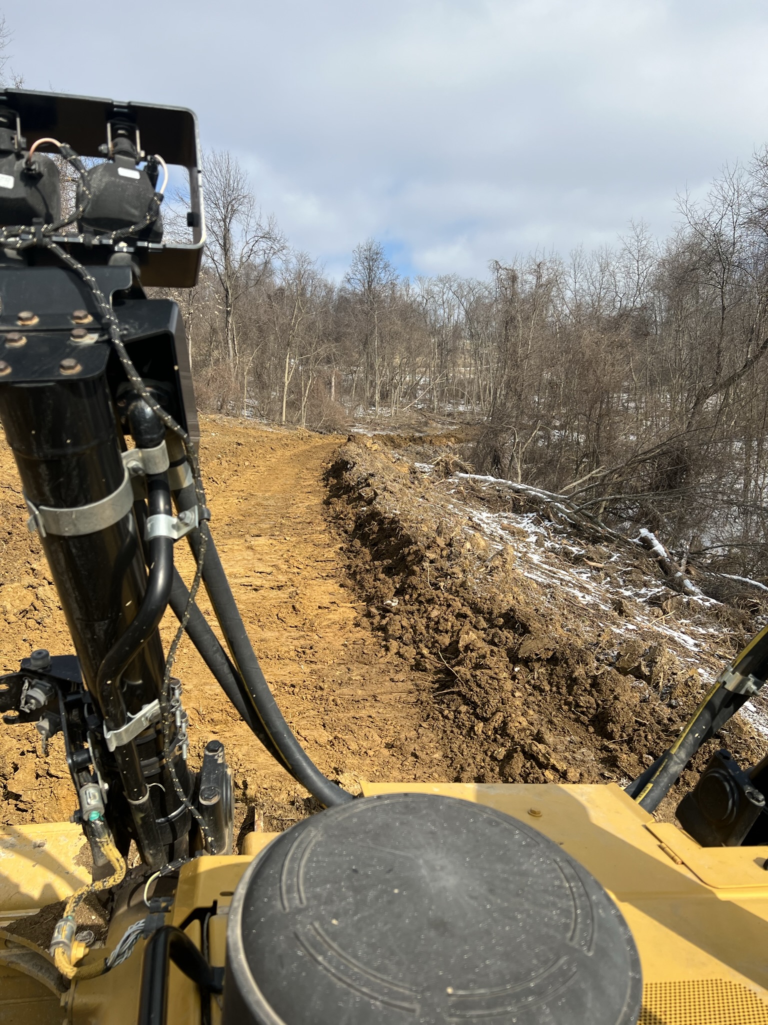 Dozer operator view cutting road bed through snowy woods