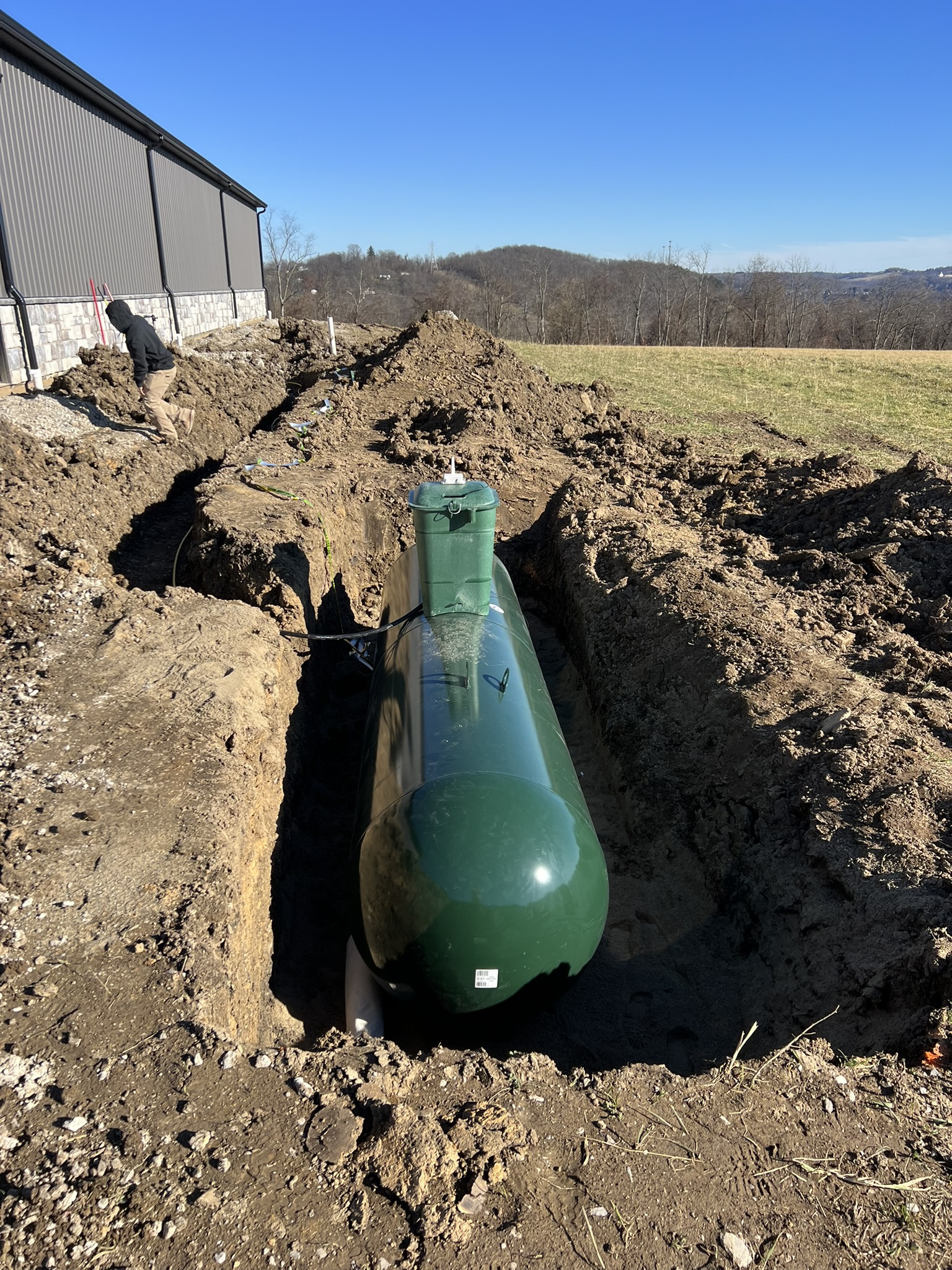 Underground propane tank being set next to barn