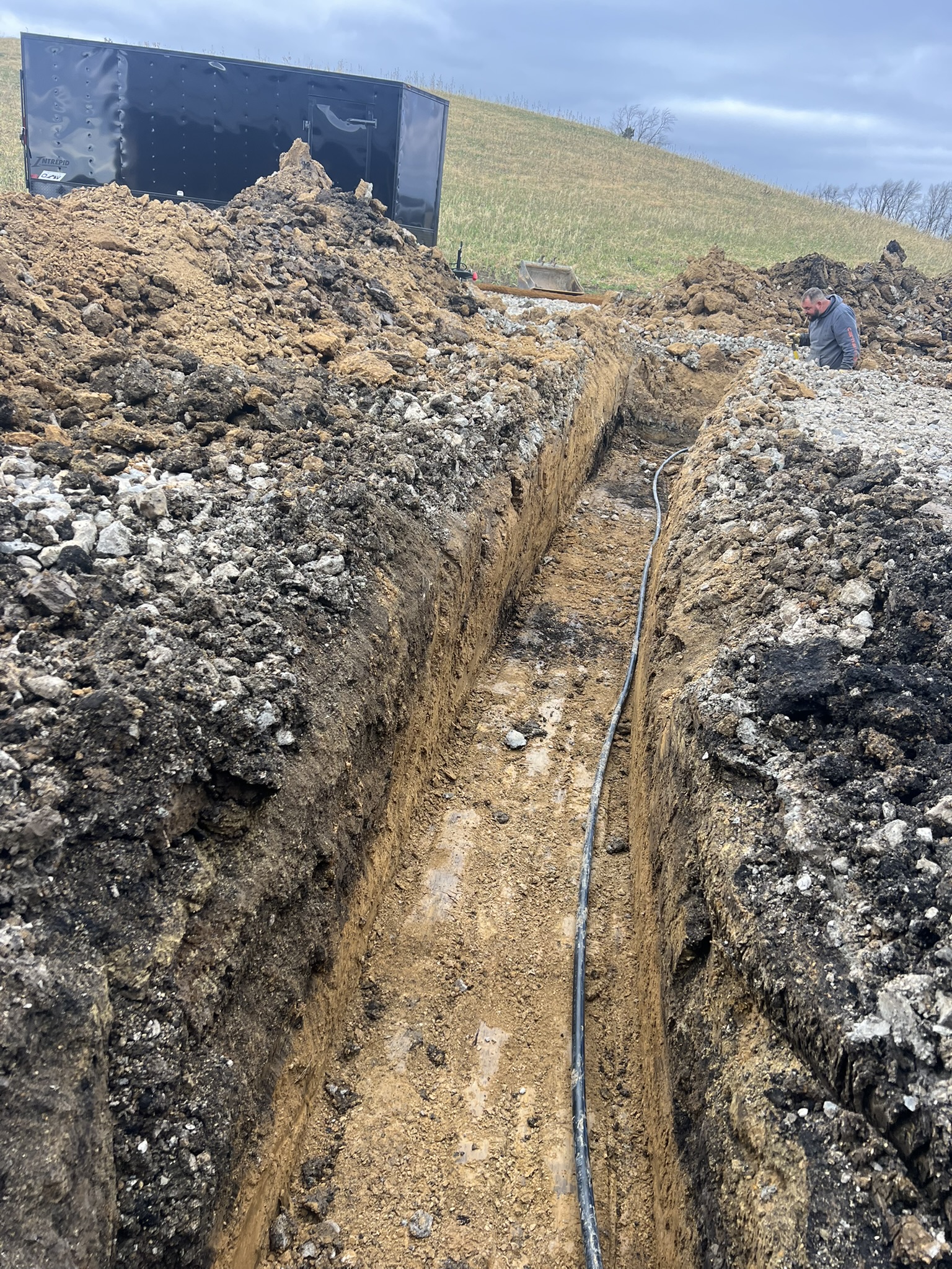 Utility trench with conduit being laid