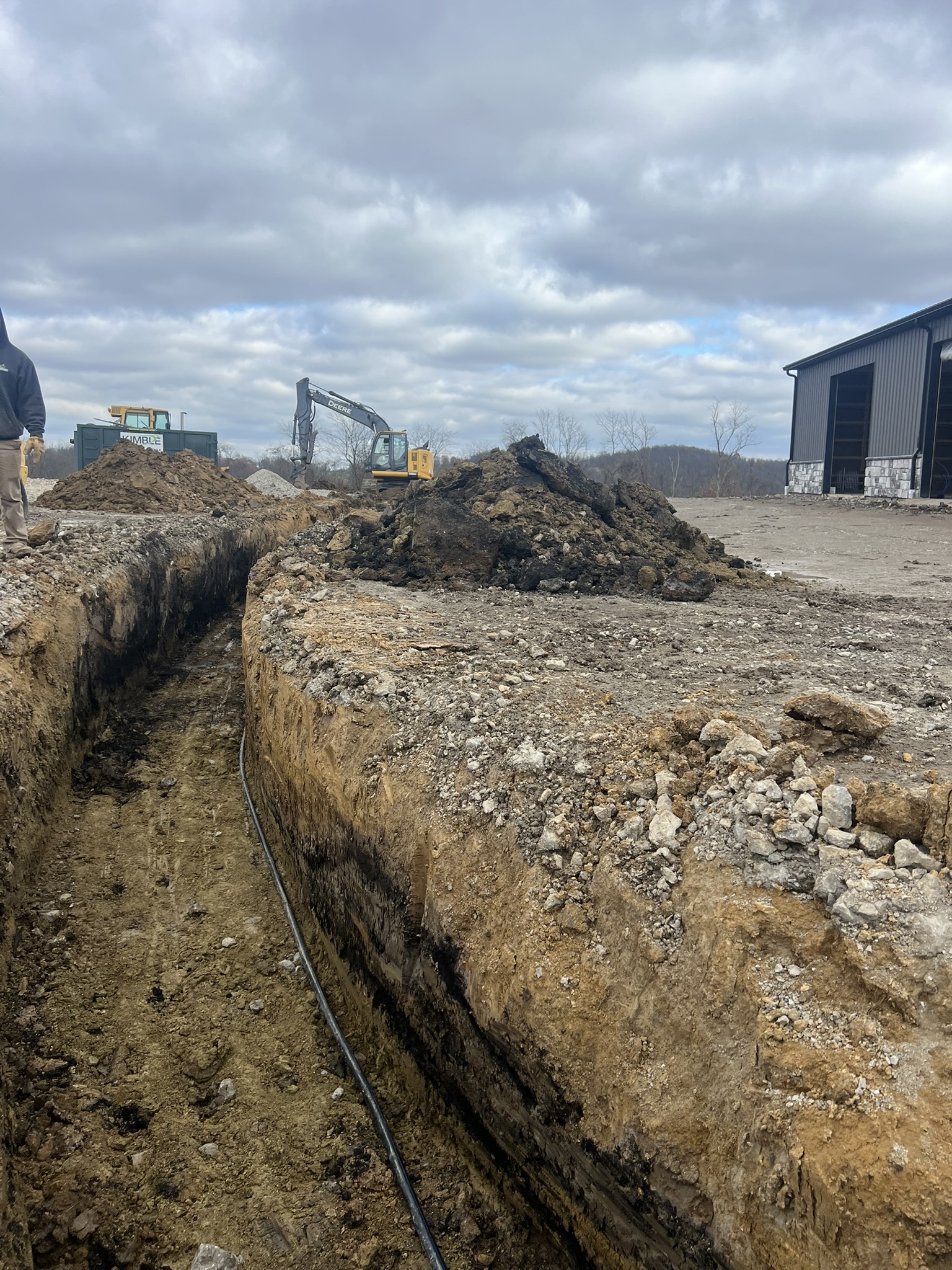Long utility trench with John Deere excavating