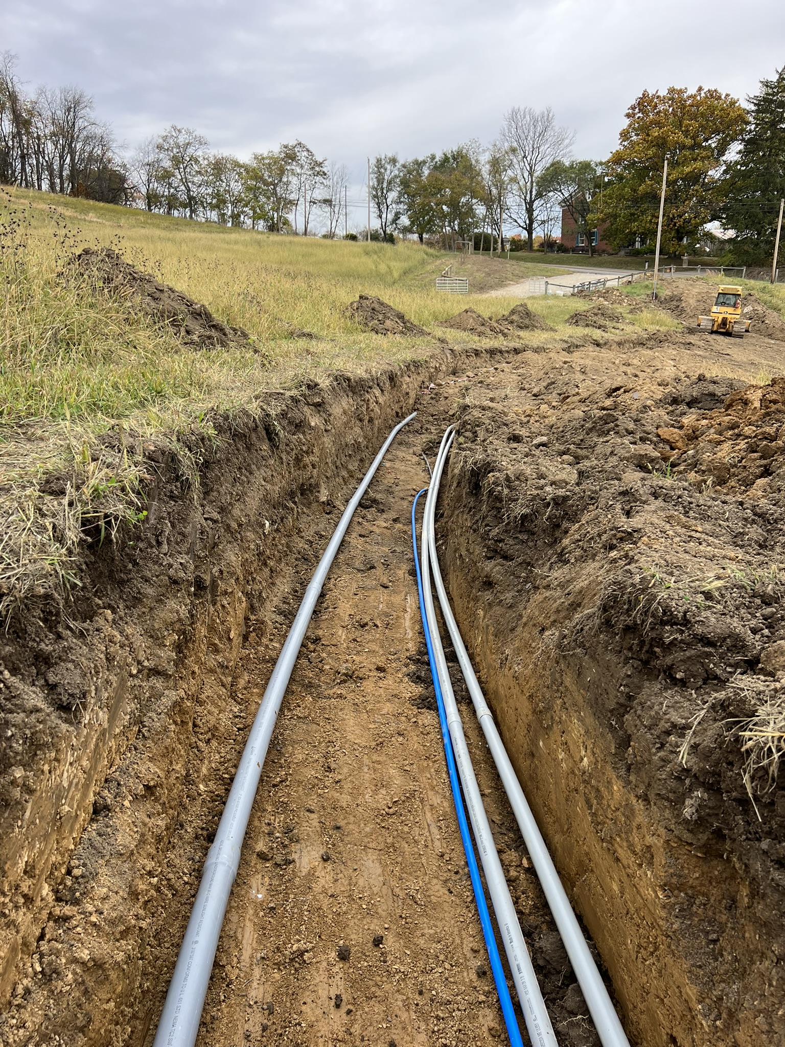 Long trench with gray conduit and blue water line