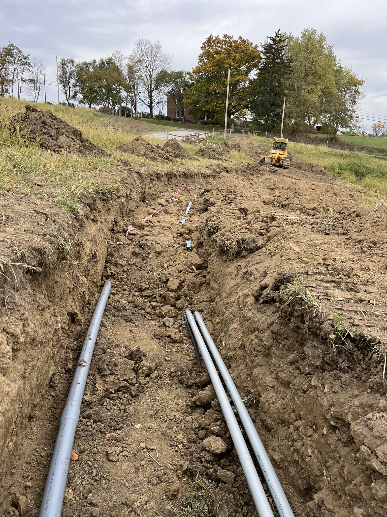 Three-pipe run in trench with skid steer backfilling