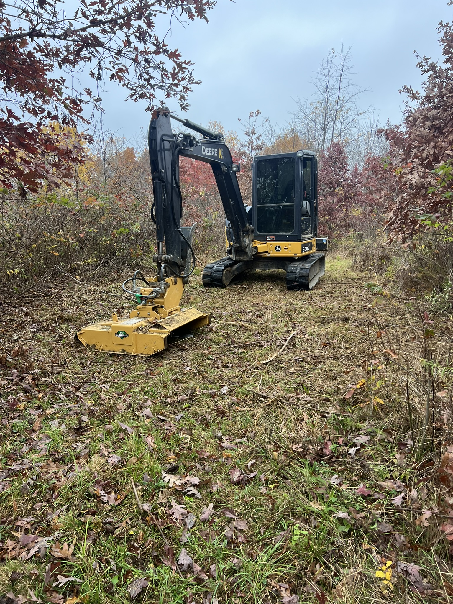 John Deere 50G with mulcher head in wooded area — fall foliage